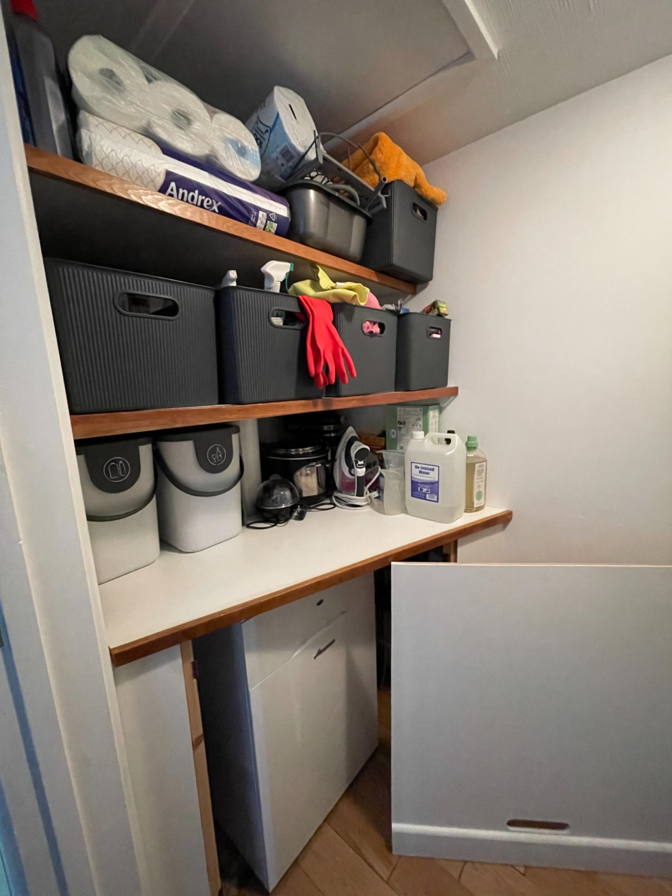 Finished work - boiler without front panel Organised storage area with shelves containing cleaning supplies and boxes above boxed in boiler, with front panel removed.