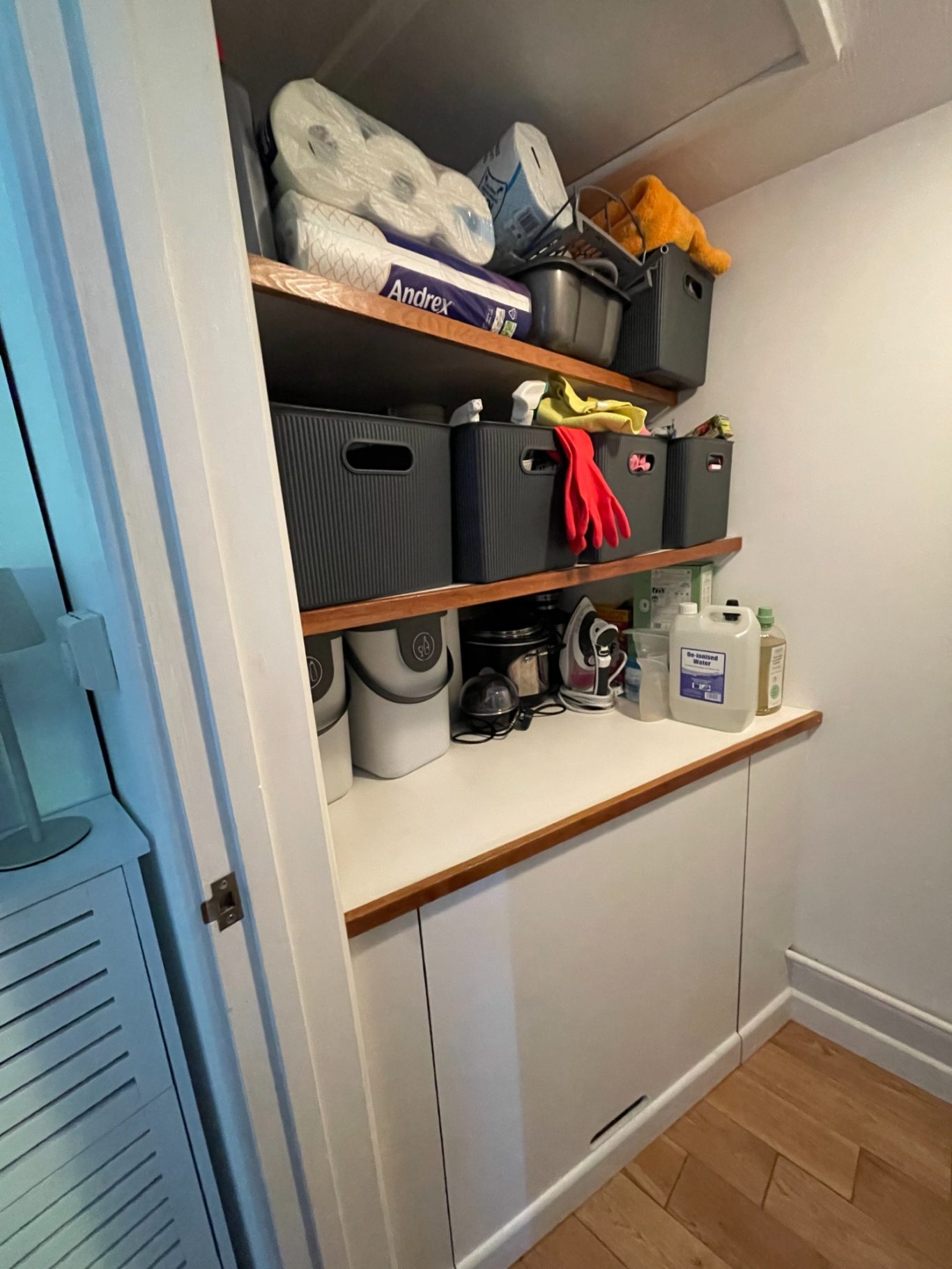Finished work - boiler Organised storage area with shelves containing cleaning supplies and boxes above boxed in boiler.