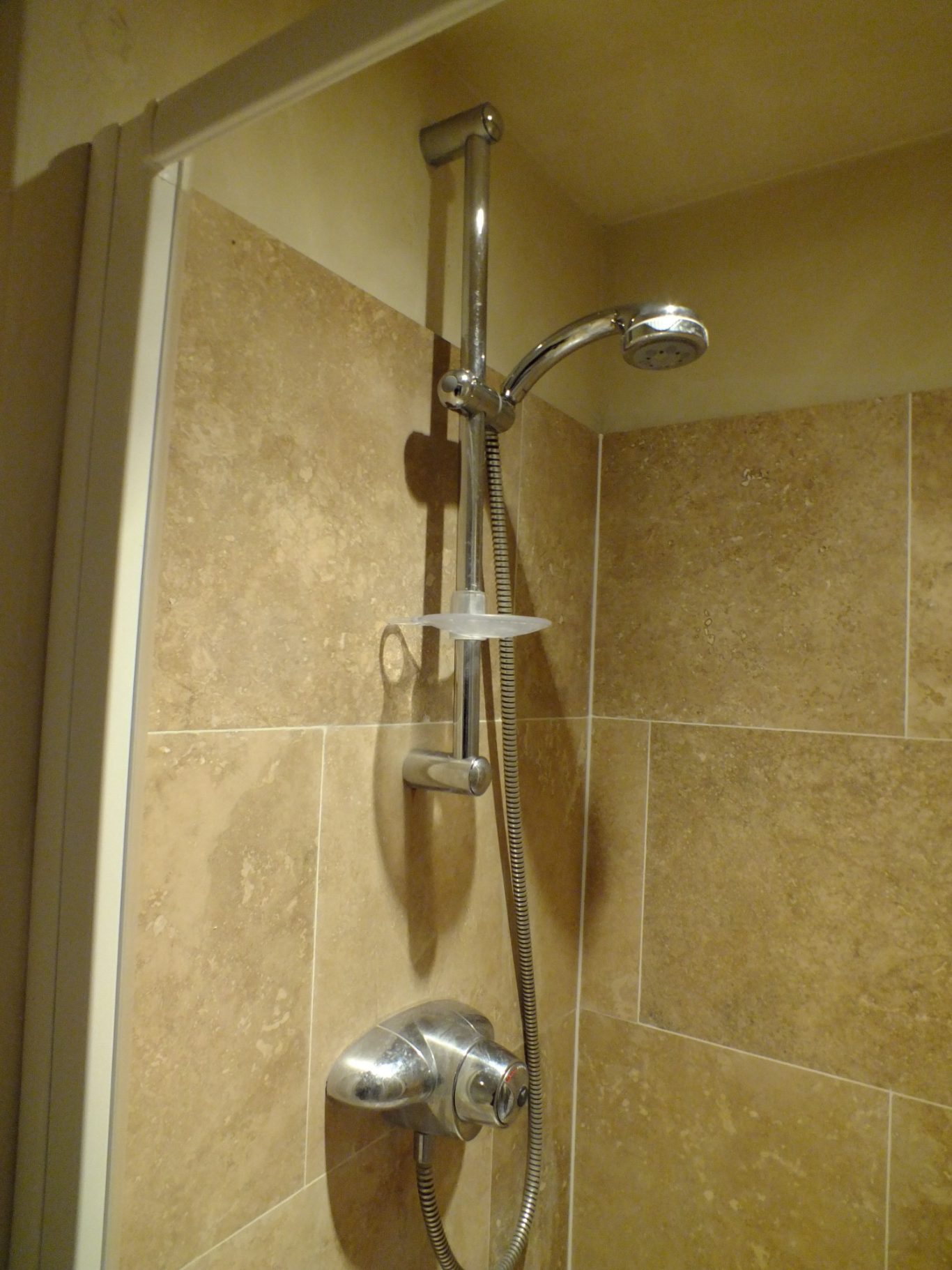 Original shower head and mixer tap A showerhead and adjustable rail in a tiled bathroom.